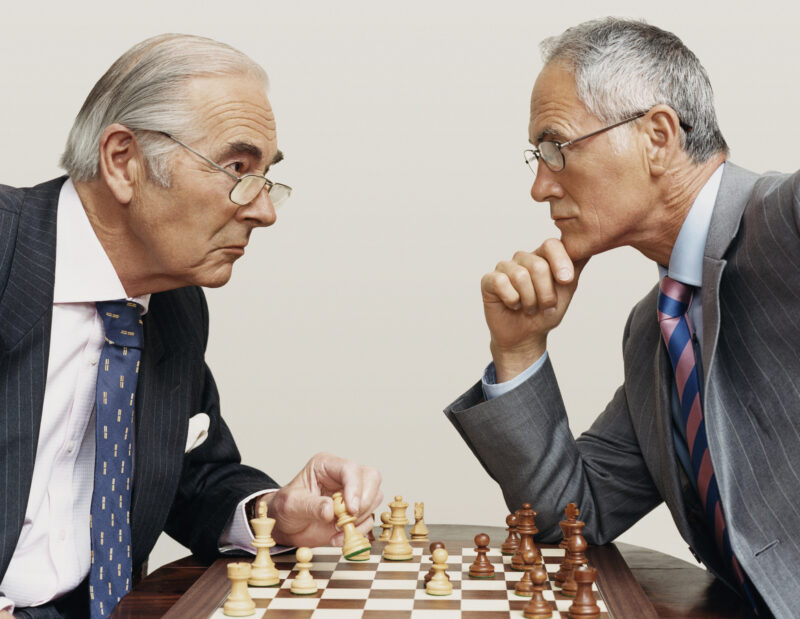 Two Businessmen Looking Face to Face and Playing Chess